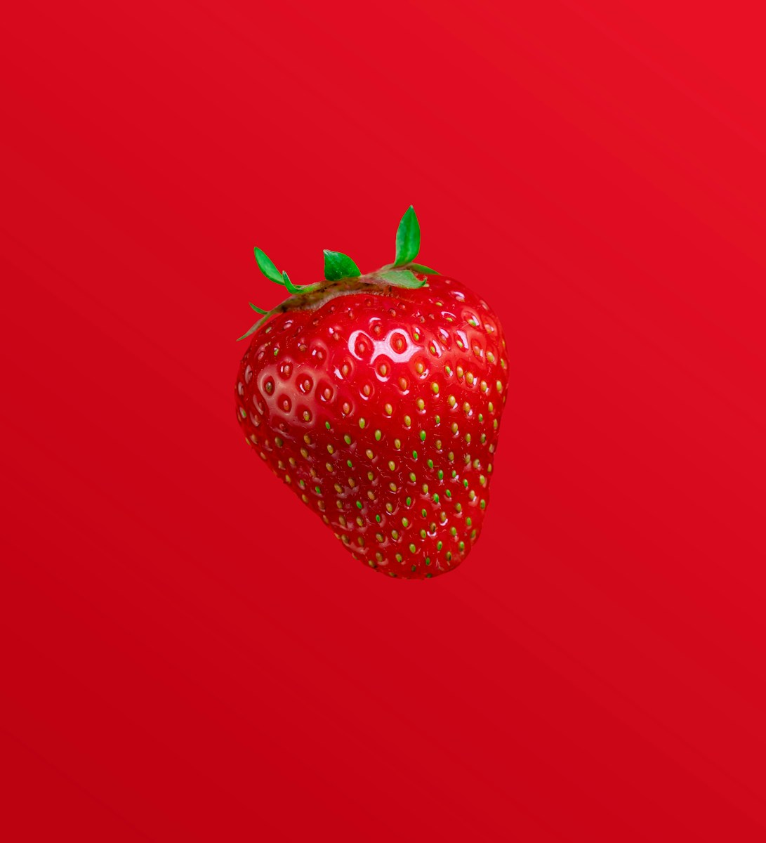 A red strawberry against a red background.