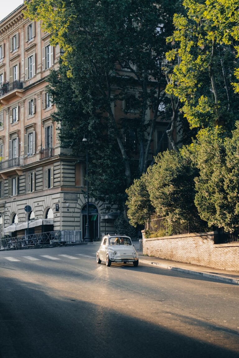 Classic white car on a sunny street with historic buildings.