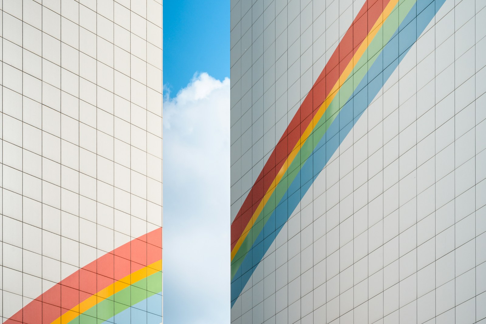 White grid buildings featuring diagonal rainbow stripes against blue sky.